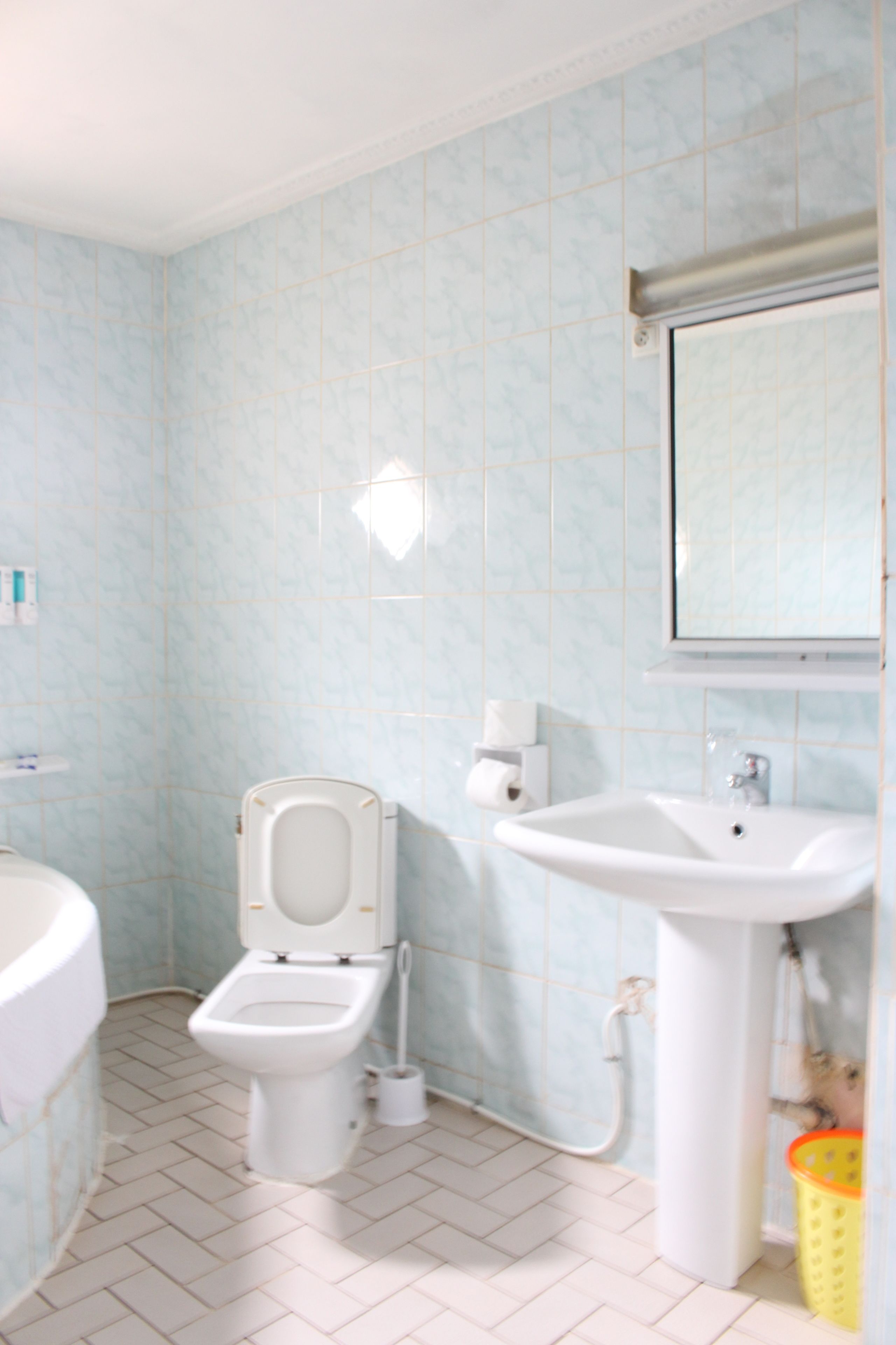 Un baño con inodoro, lavamanos y paredes con azulejos.