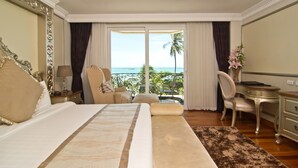 A spacious bedroom with a large bed, a desk, and a chair. There is a balcony with a view of the ocean. - LK The Empress Pattaya (Pattaya)