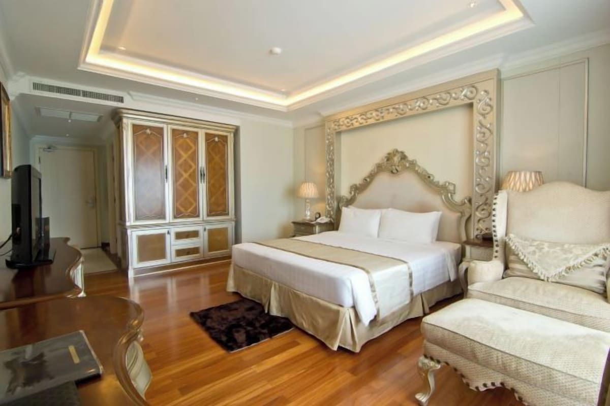 Una habitación de hotel con una cama grande, un escritorio de madera, una silla y un armario.
