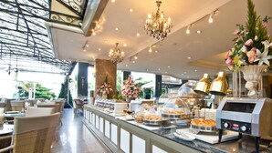 A buffet area with a variety of food items, a coffee machine, and a decorative flower arrangement. - LK The Empress Pattaya (Pattaya)