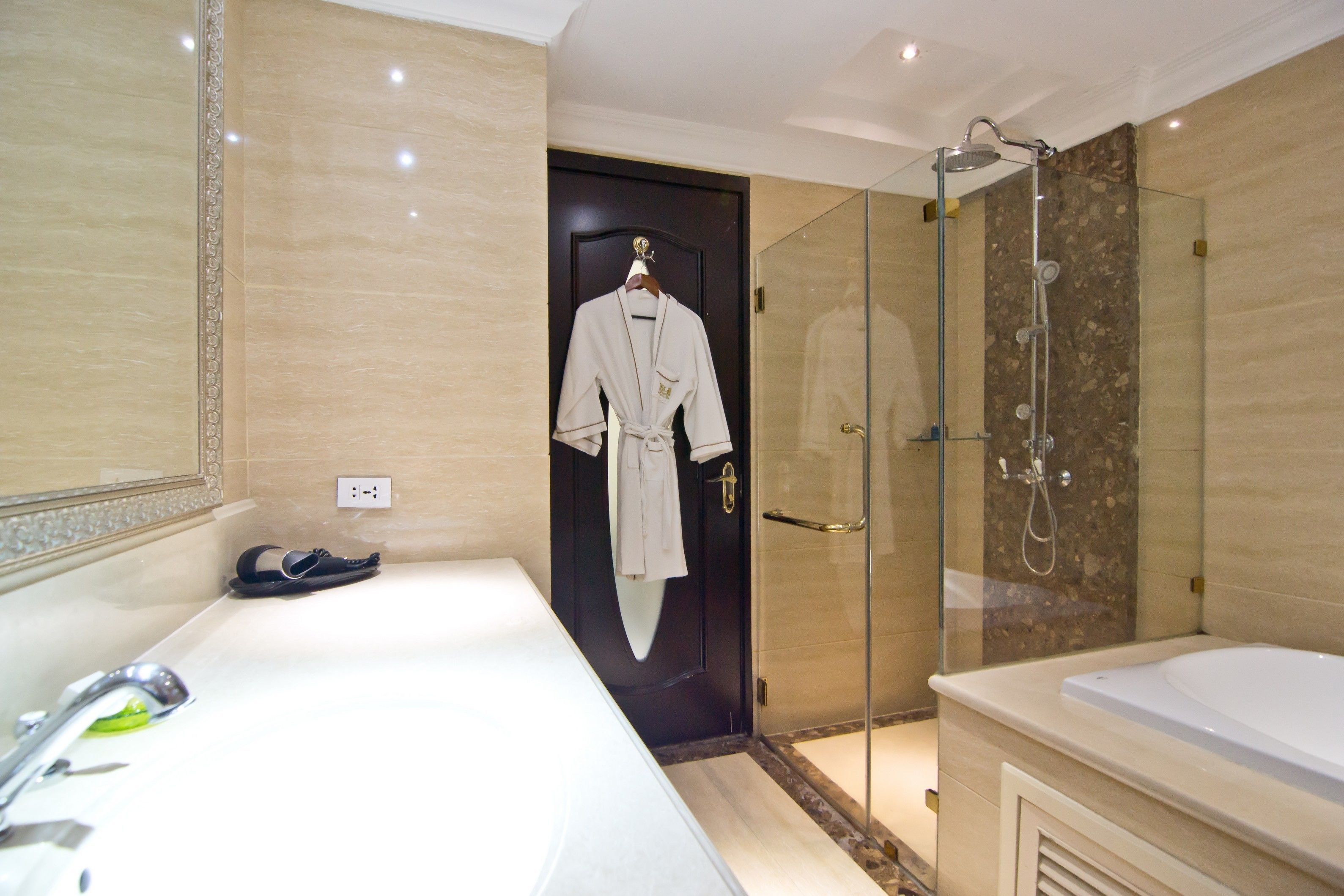 Une salle de bain moderne avec une grande baignoire, une douche à parois de verre et un peignoir accroché à la porte.
