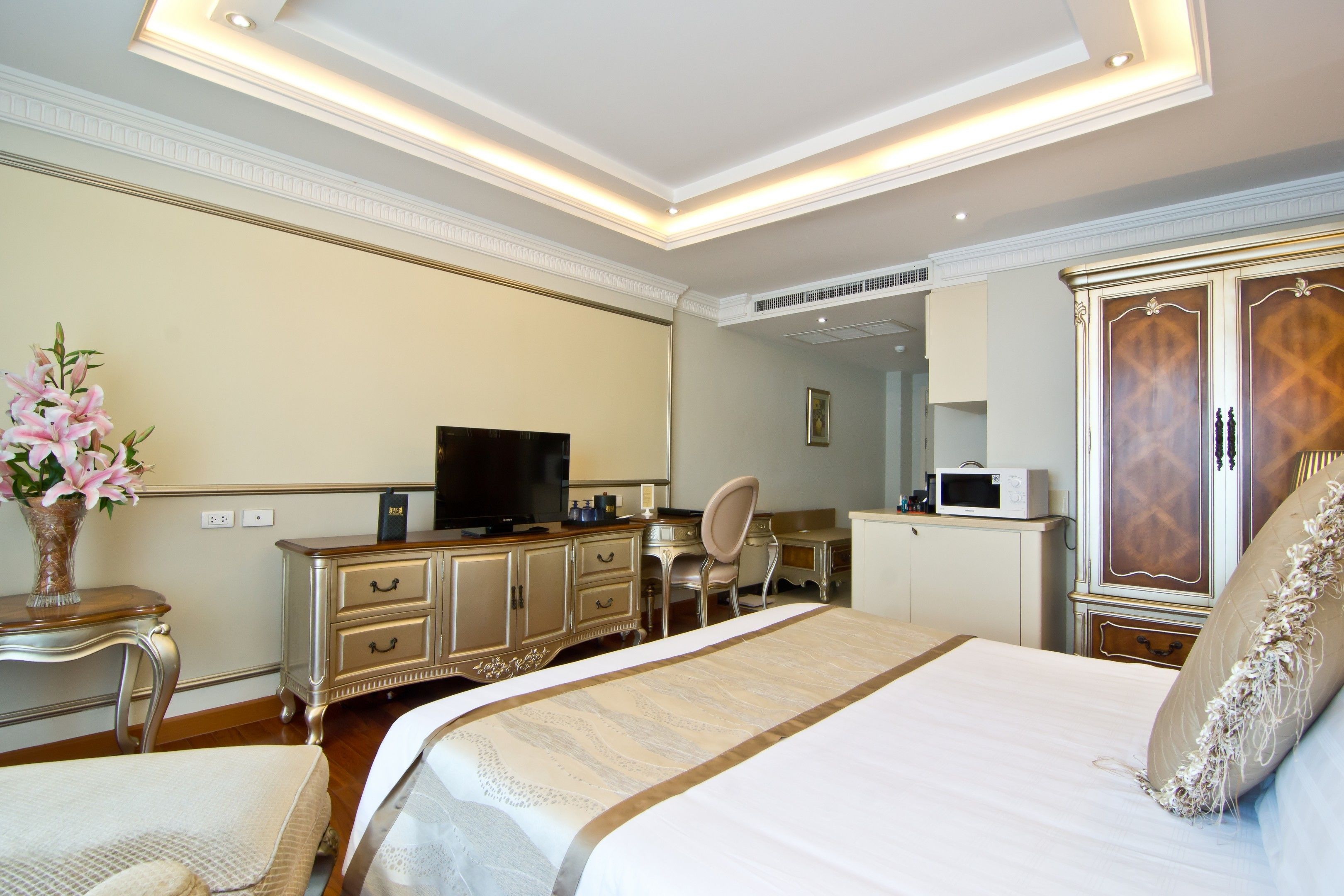 Una habitación de hotel con una cama grande, un escritorio, un televisor y un armario.