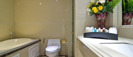 A bathroom with a bathtub, toilet, and shower. There is a vase with flowers on the vanity.