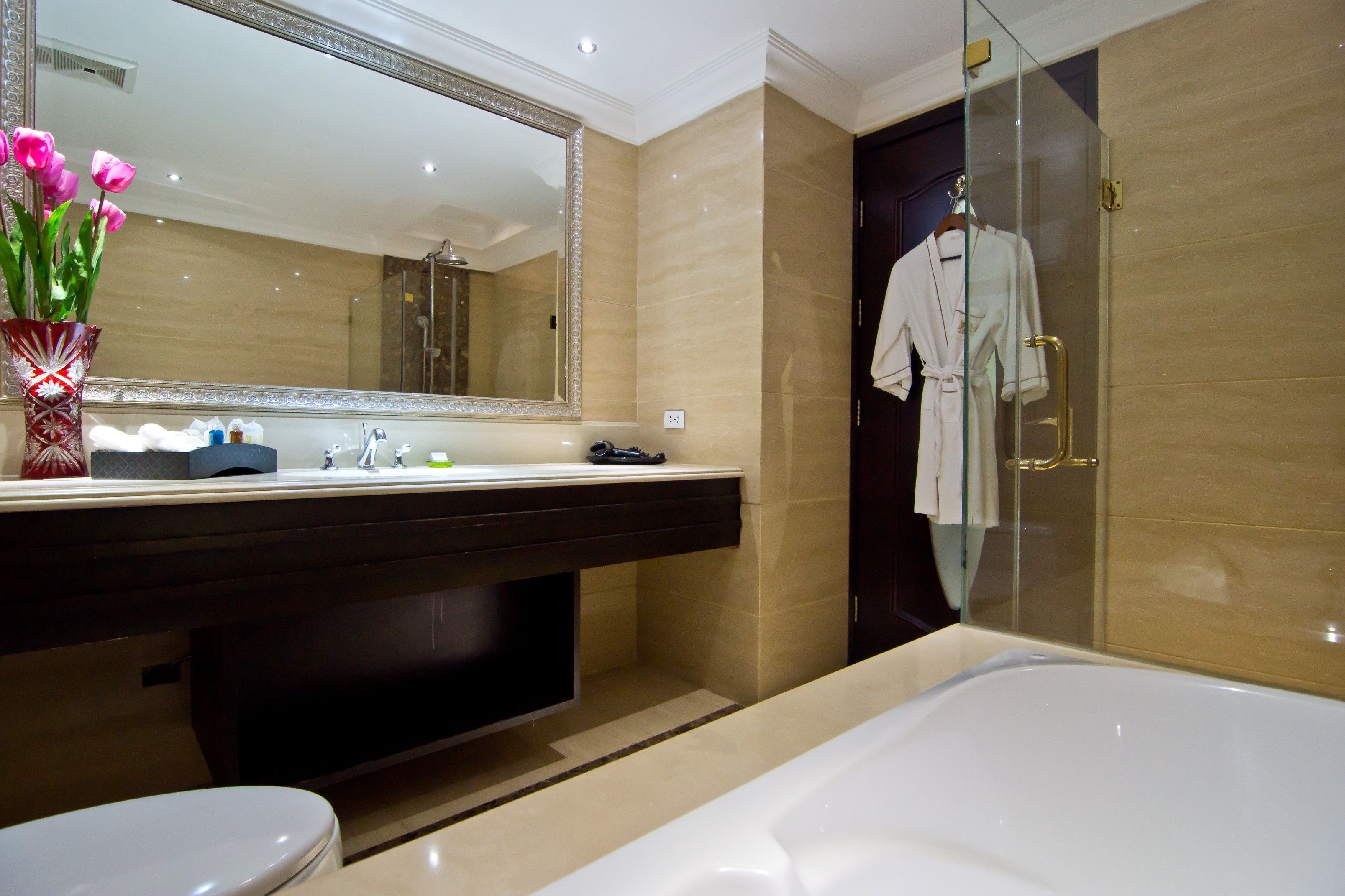 Un bany modern amb un mirall gran, una banyera, un vàter i un lavabo amb rentapans.
