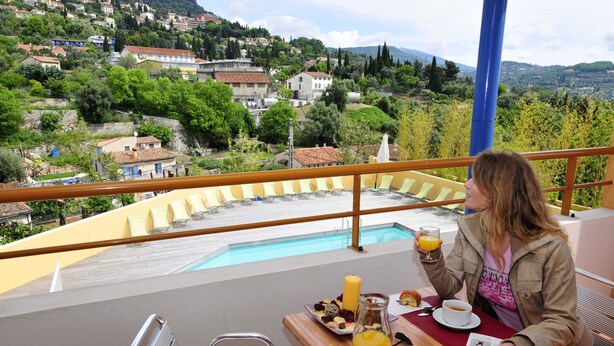 En terrasse med pool, spisebord og stole med udsigt over en malerisk landsby.