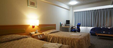A hotel room with two beds, a desk with a computer, a chair, and a large window with curtains.
