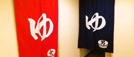 Two towels hanging on hooks, one red and one blue, with white symbols on them.