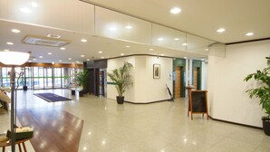 A spacious lobby with a polished floor, a reception desk, potted plants, and a large window providing natural light. - Hotel Crown Hills Himeji (Himeji)