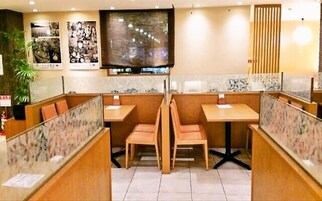 Ein Restaurant mit Boxsitzplätzen, einem Fernsehbildschirm und gerahmten Bildern an der Wand.