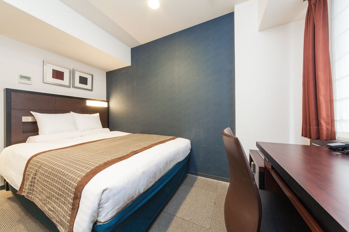 Une chambre d’hôtel avec un lit, un bureau et une chaise.