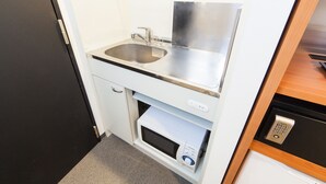 Eine kompakte Küchenzeile mit Spüle aus Edelstahl, einer Mikrowelle und einem eingebauten Backofen.