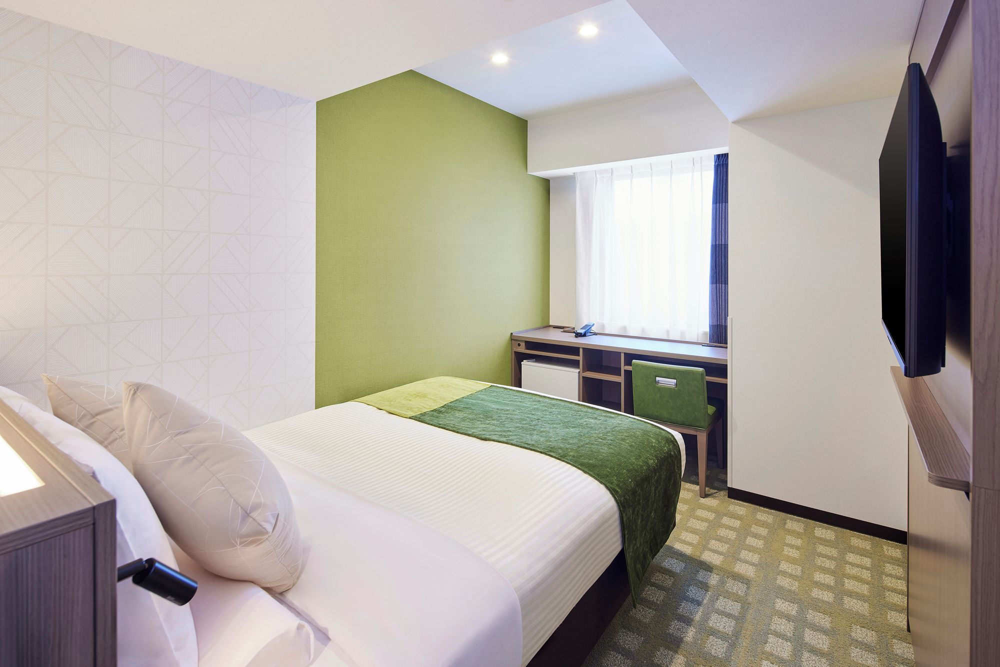 A hotel room with a bed, a desk, and a television.