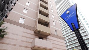 Ein mehrstöckiges Hotel mit modernem Design, erkennbar an der gut sichtbaren Beschilderung für Hotel Mystays im Stadtgebiet Sakaisuji-Honmachi.