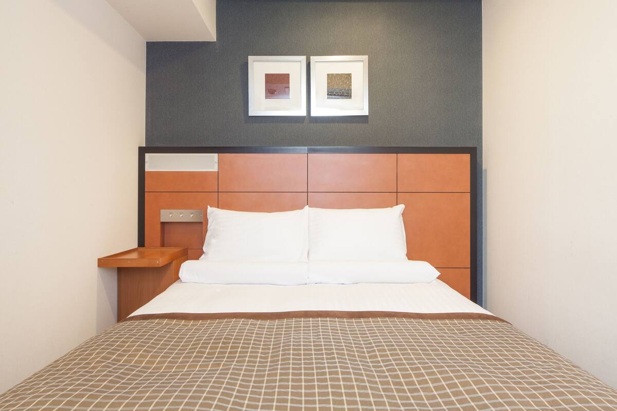 Une chambre d’hôtel avec un lit, une table de chevet et deux tableaux encadrés au mur.