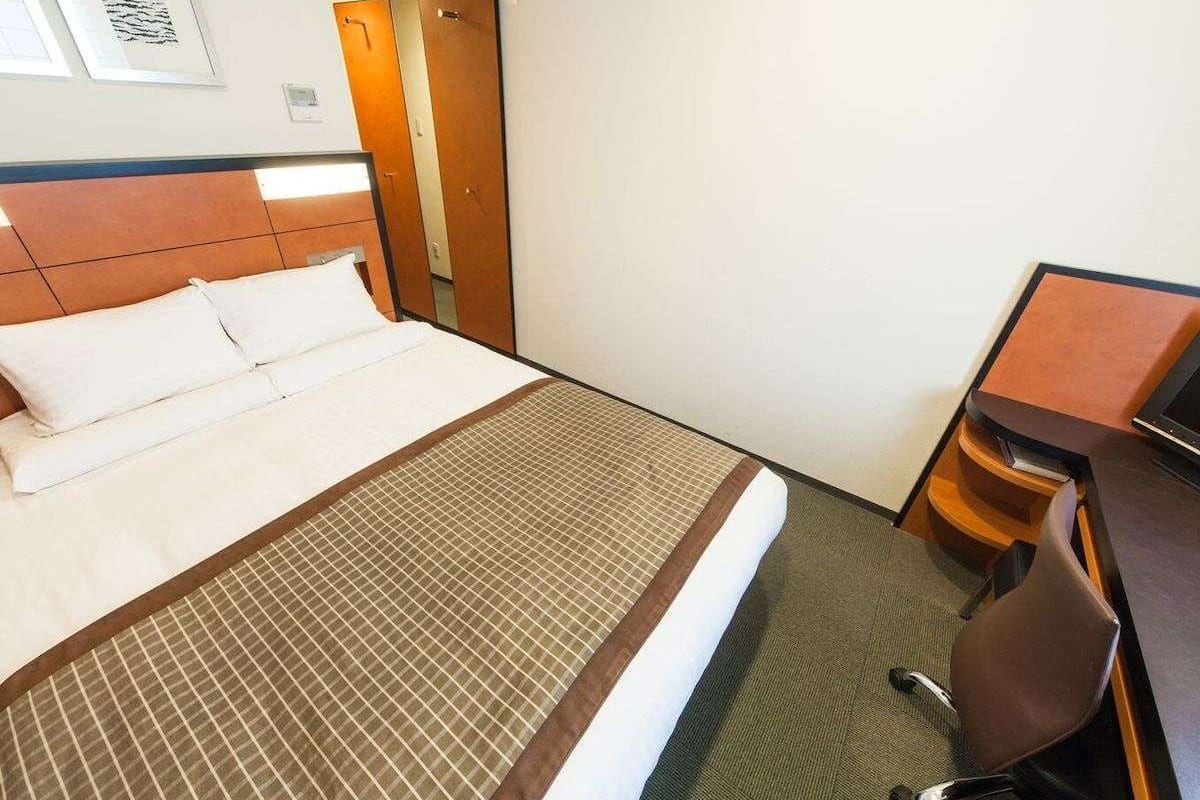 Une chambre d’hôtel avec un lit, un bureau et une chaise.