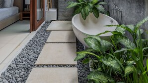 A modern bathroom with a freestanding bathtub, a shower, and a decorative wall. - Chandra Bali Villas (Seminyak)