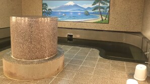 A spa area with a large stone feature, a tiled floor, and a wall mural depicting a beach scene. - Tokyo Business Hotel (Tokyo)