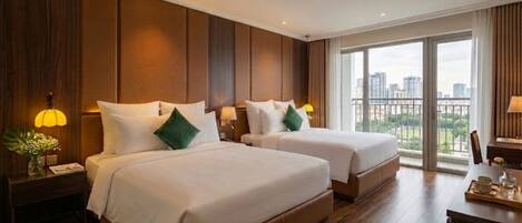 A hotel room with two beds, wooden paneling, a city view, and a dining area with a tray.