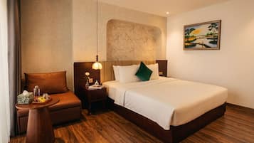 Ein Hotelzimmer mit Bett, Nachttisch, Lampe, Stuhl und einem Bild an der Wand.