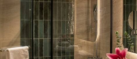 A modern bathroom with a glass-enclosed shower, a toilet, and a vanity with a mirror and towel rack.