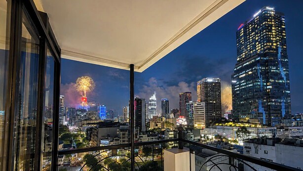 Een balkon met uitzicht op een verlichte stad, inclusief gebouwen en vuurwerk.