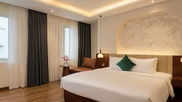 A hotel room with a large bed, a small side table with a vase, a window with curtains, and a wall with a marble-like design.