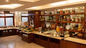 Een keuken met een buffetopstelling, houten kastjes en diverse keukengerei en flessen.