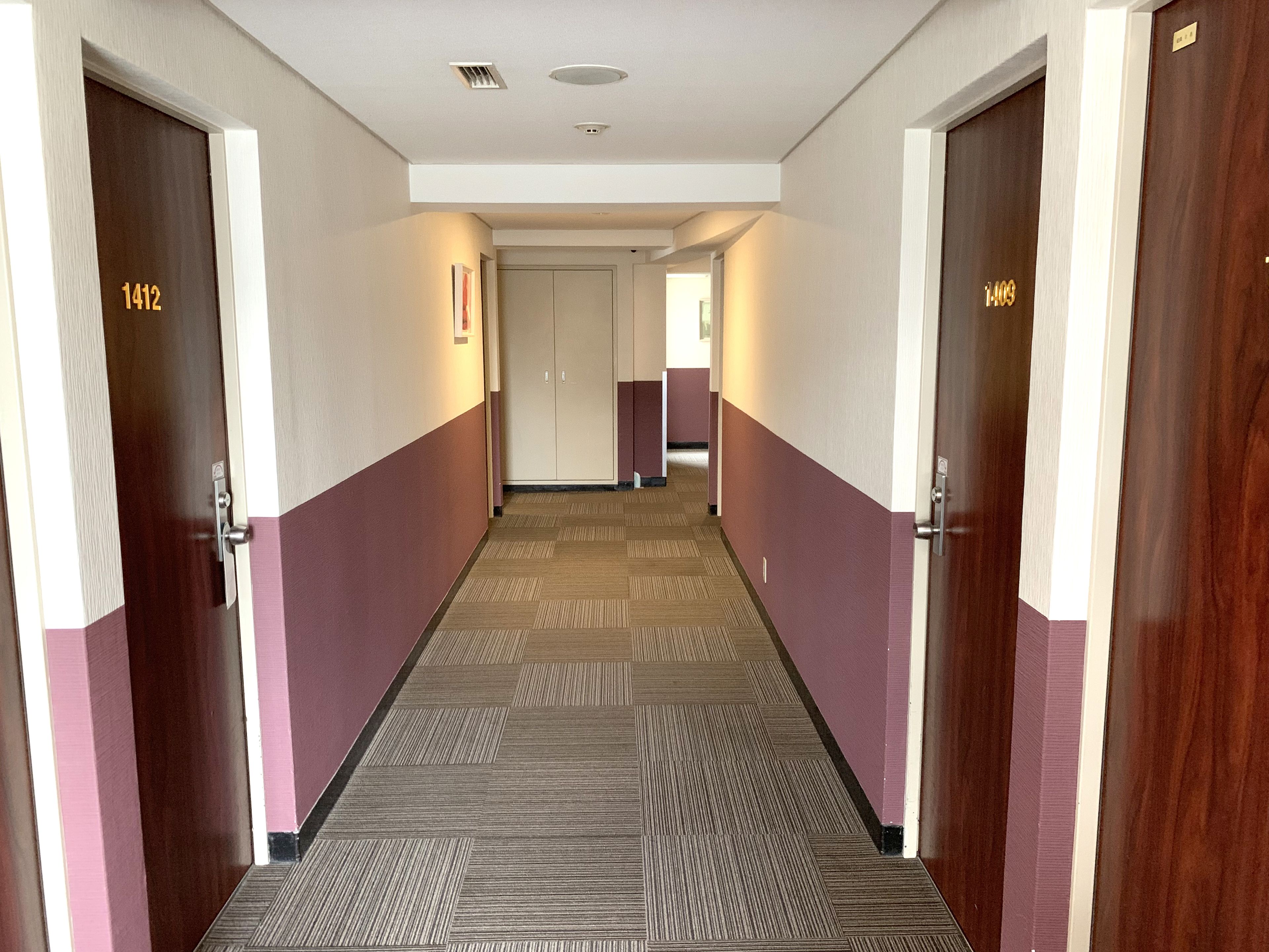 A hotel hallway with doors numbered 1412 and 1409, carpeted floor, and a ceiling light.