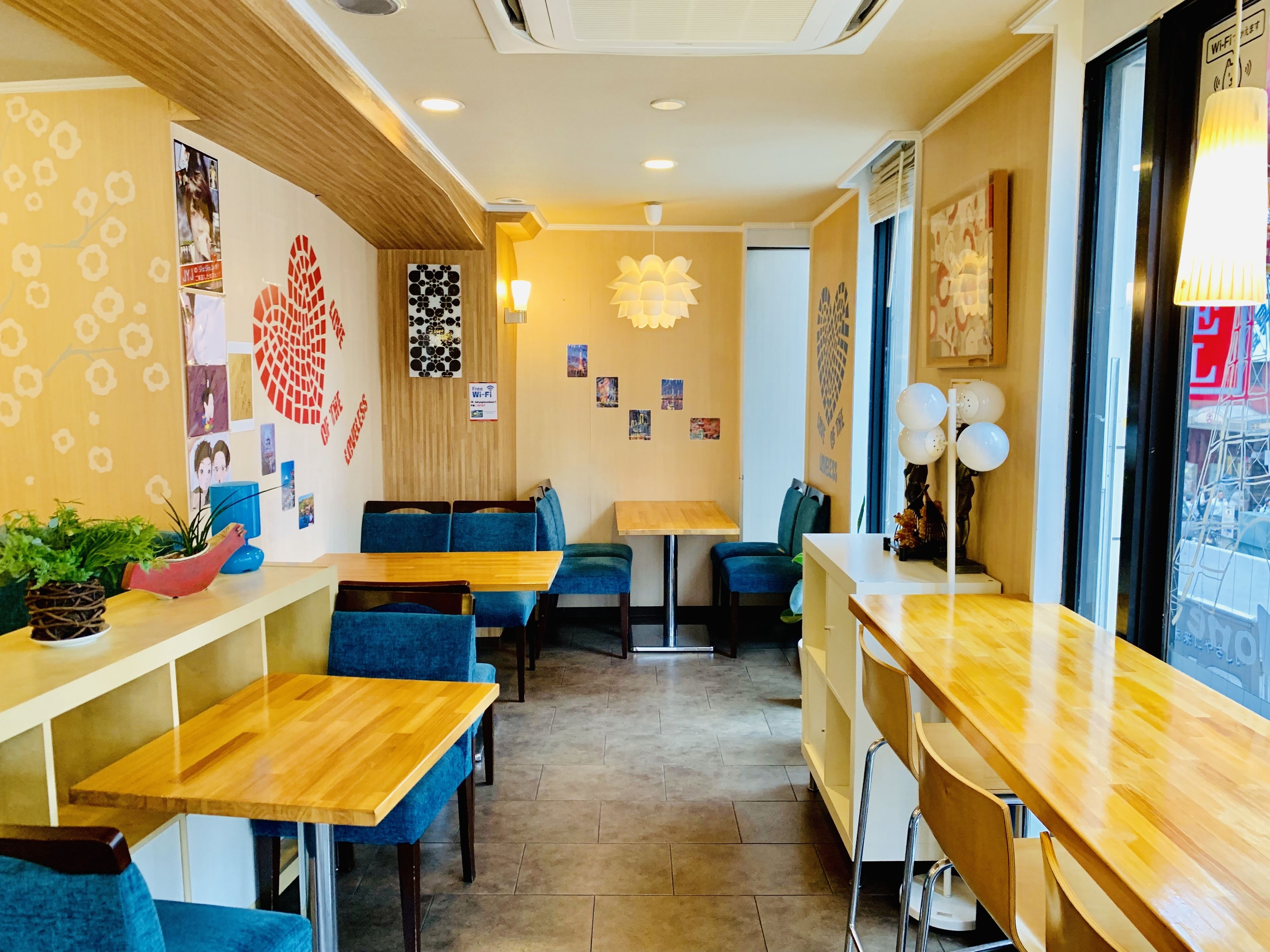 A restaurant interior with wooden tables and blue upholstered chairs, a wall decorated with photos and a Wi-Fi sign.
