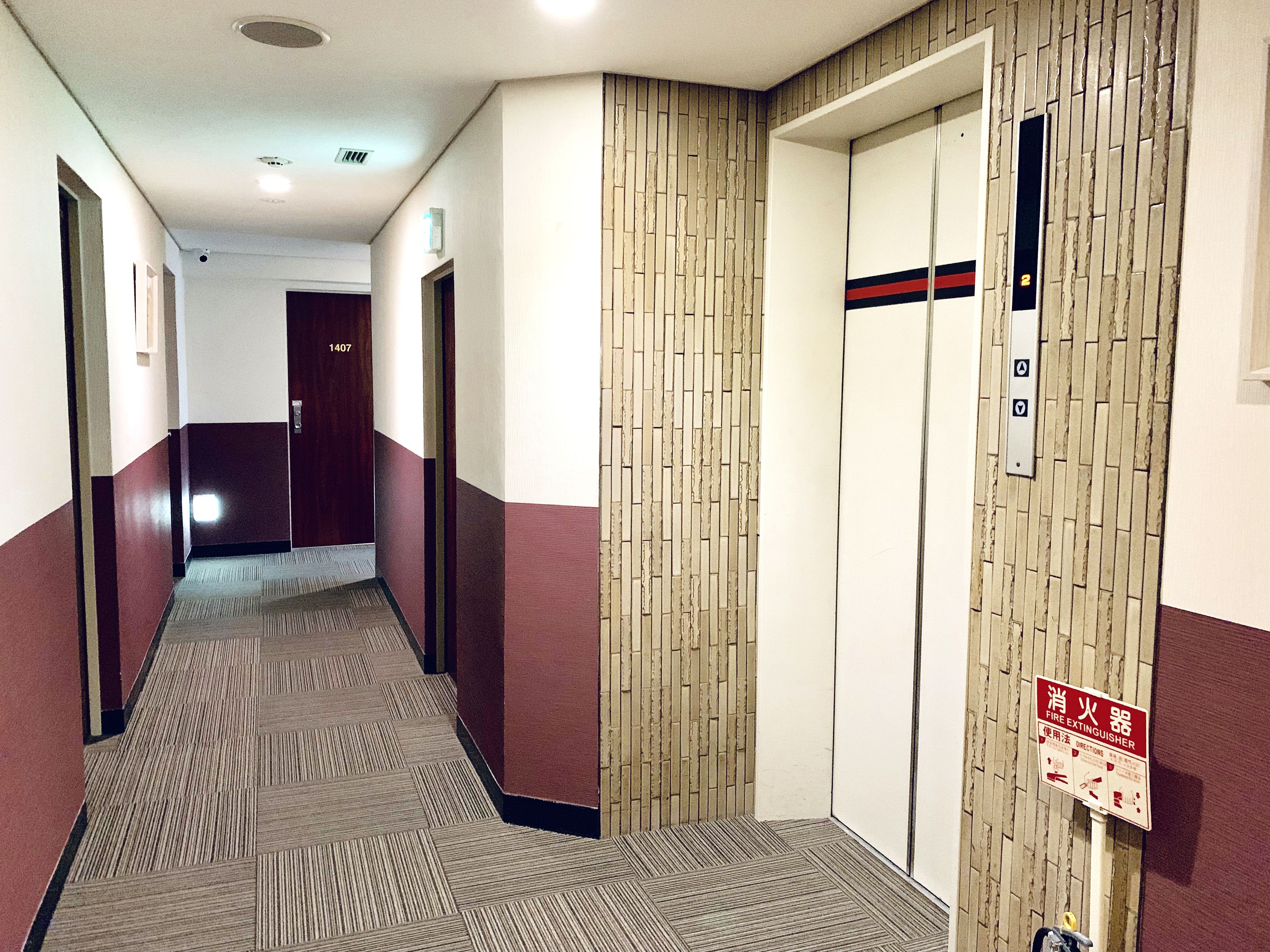 Passadís d'hotel amb sòl de moqueta, parets de fusta i un senyal d'extintor.