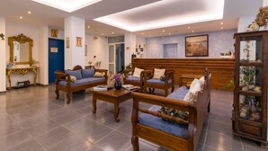 A spacious lobby with wooden furniture, a reception desk, and a large mirror.