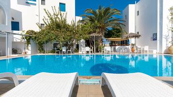 Una piscina al aire libre, sombrillas, sillones reclinables de piscina