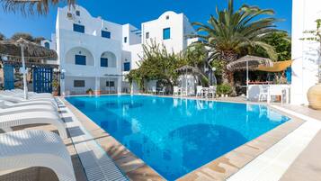 Una piscina al aire libre, sombrillas, sillones reclinables de piscina