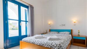 A bedroom with a bed, a nightstand, a lamp, and a window with curtains.