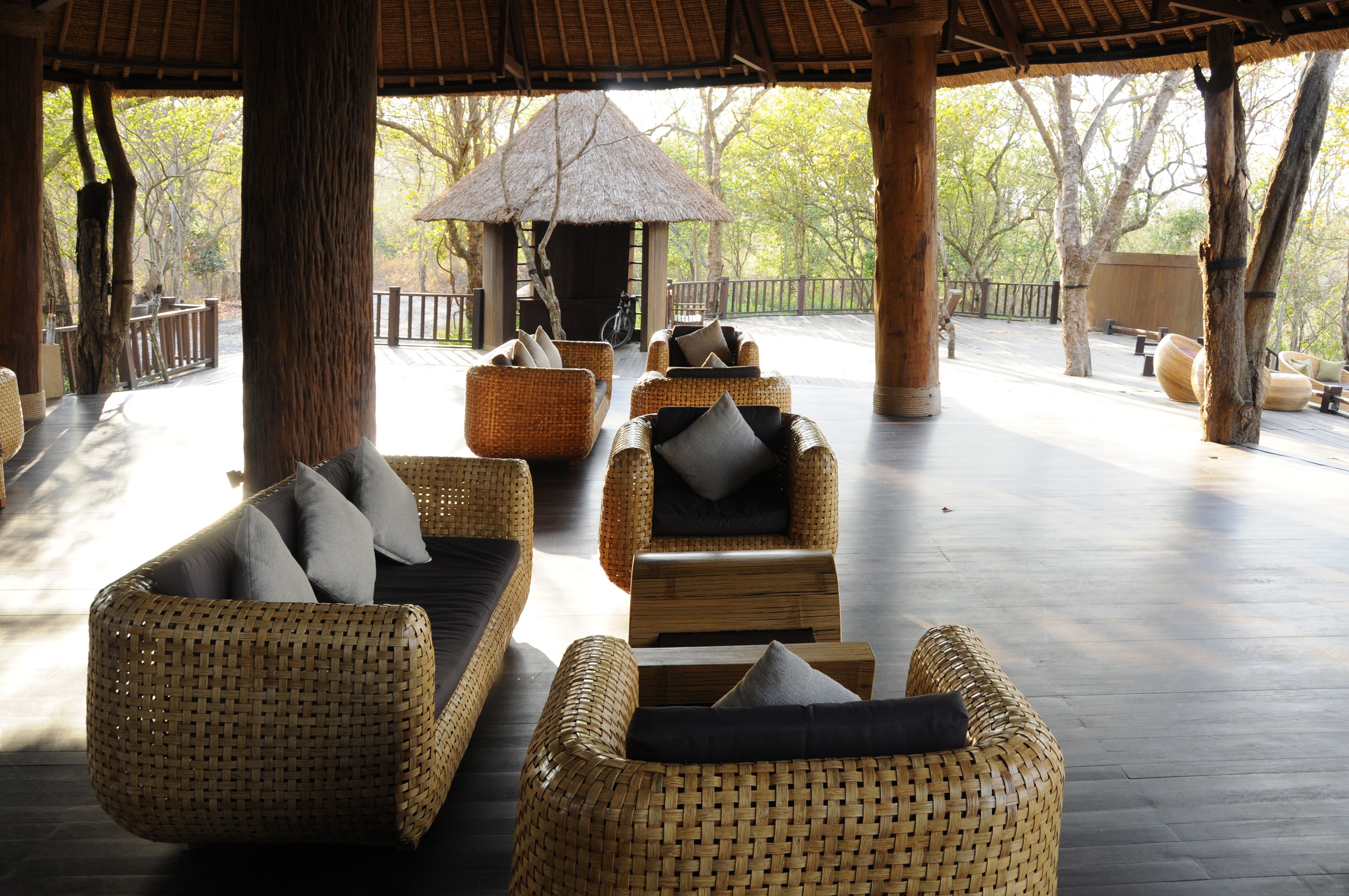 A covered outdoor seating area with wicker furniture and a thatched-roof structure.