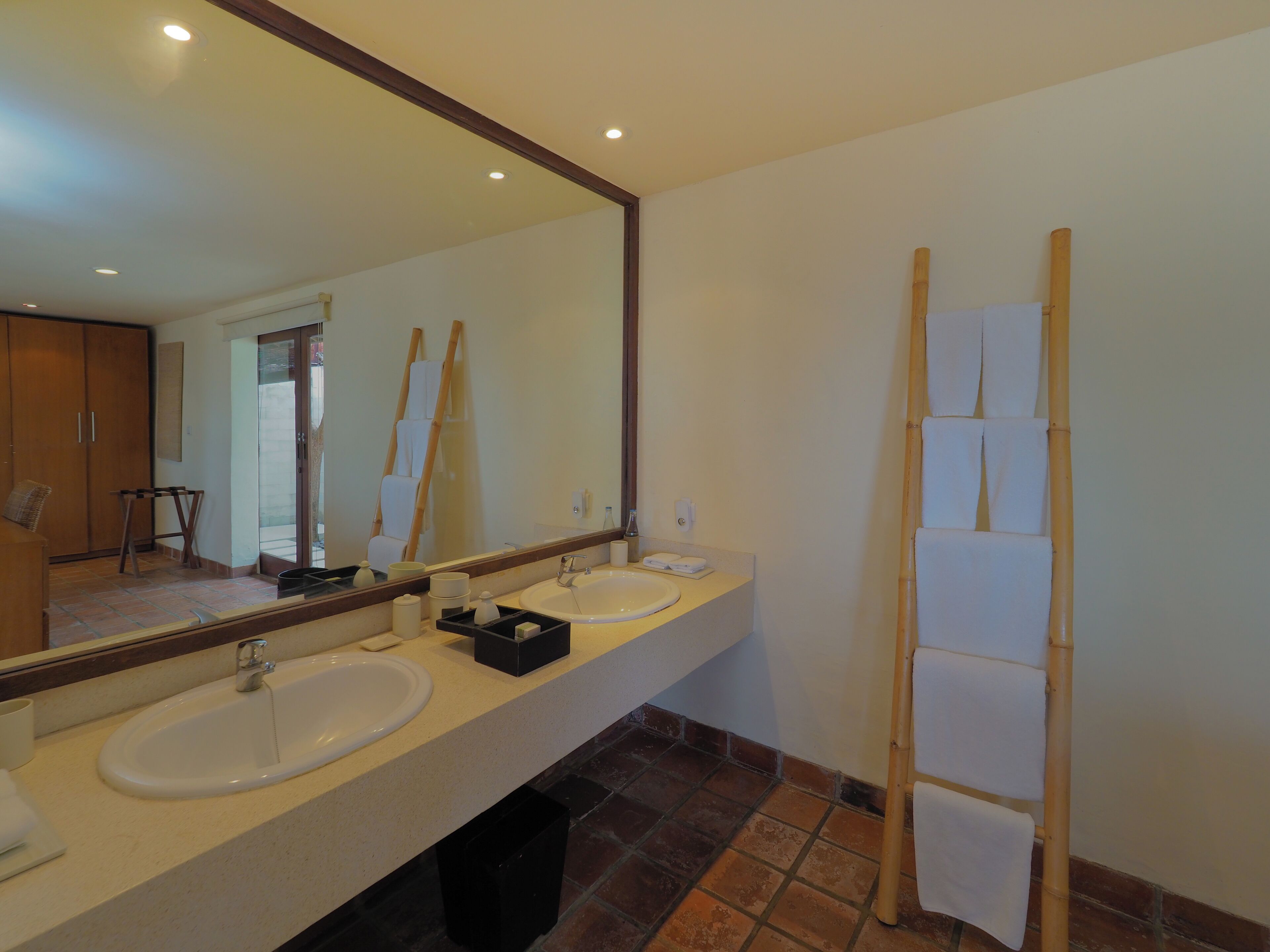 A bathroom with two sinks, a large mirror, and a bamboo shower curtain.