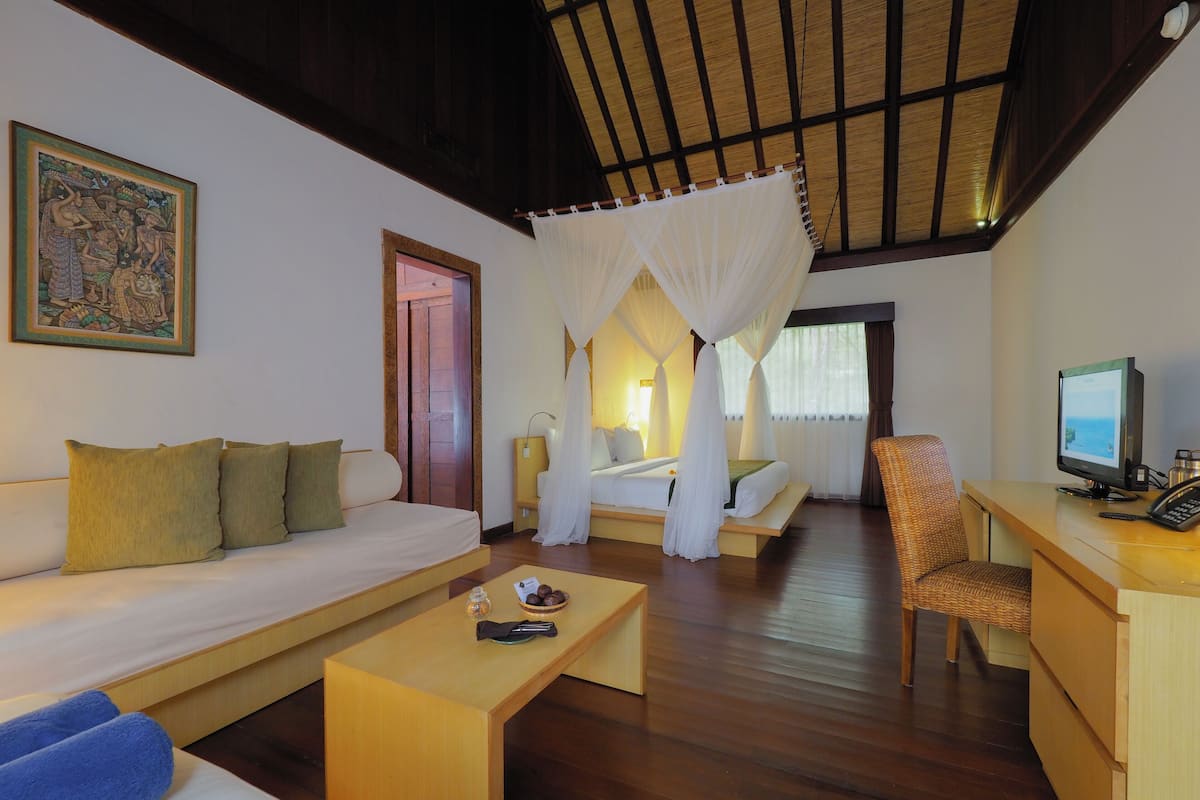 A room with a bed, a sofa, a desk, and a television.