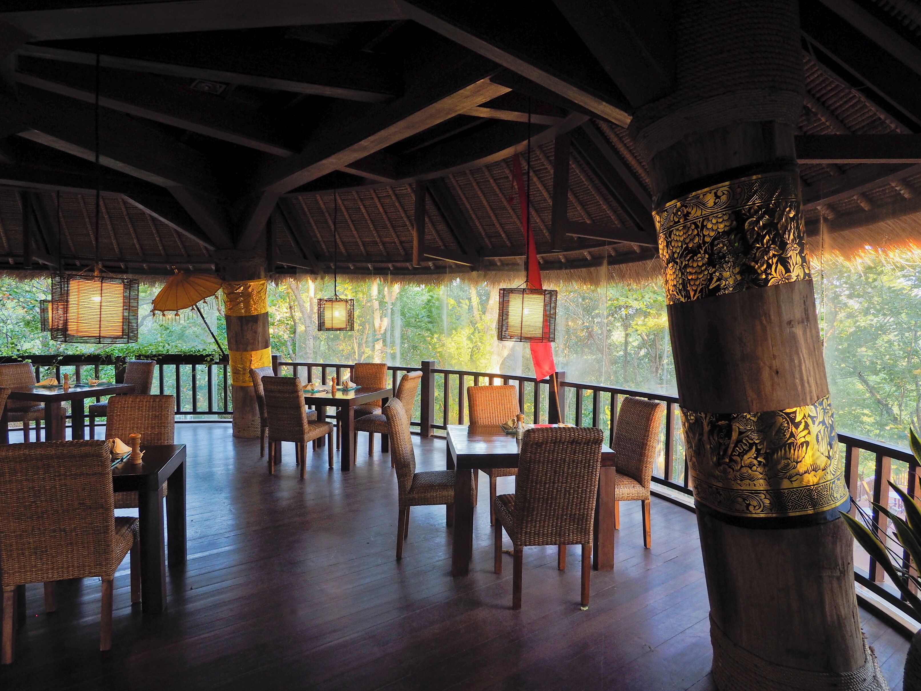 A covered outdoor seating area with wicker furniture and a thatched roof.