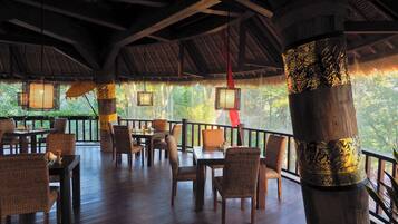A covered outdoor seating area with wicker furniture and a thatched roof.