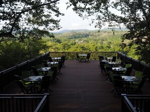 A deck with tables and chairs overlooking a forested landscape. - The Menjangan by LifestyleRetreats (Pejarakan)