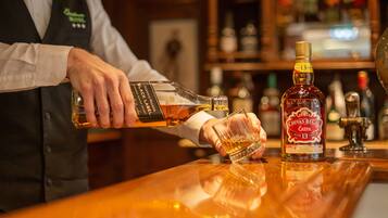 A bartender pouring whiskey into a glass at a bar.