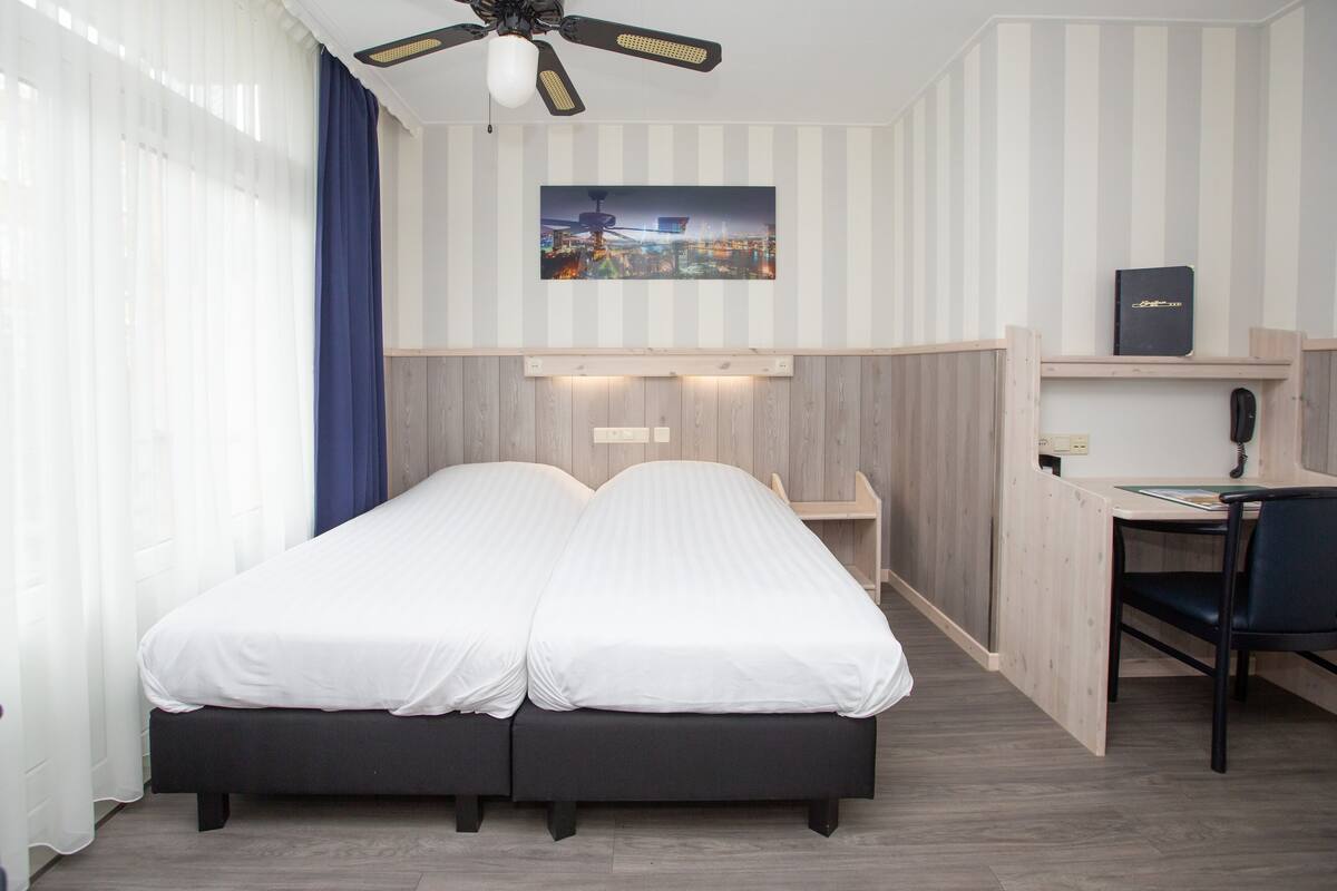 A bedroom with a bed, a desk, and a chair.