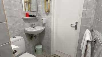 A bathroom with a toilet, sink, mirror, and towel rack.