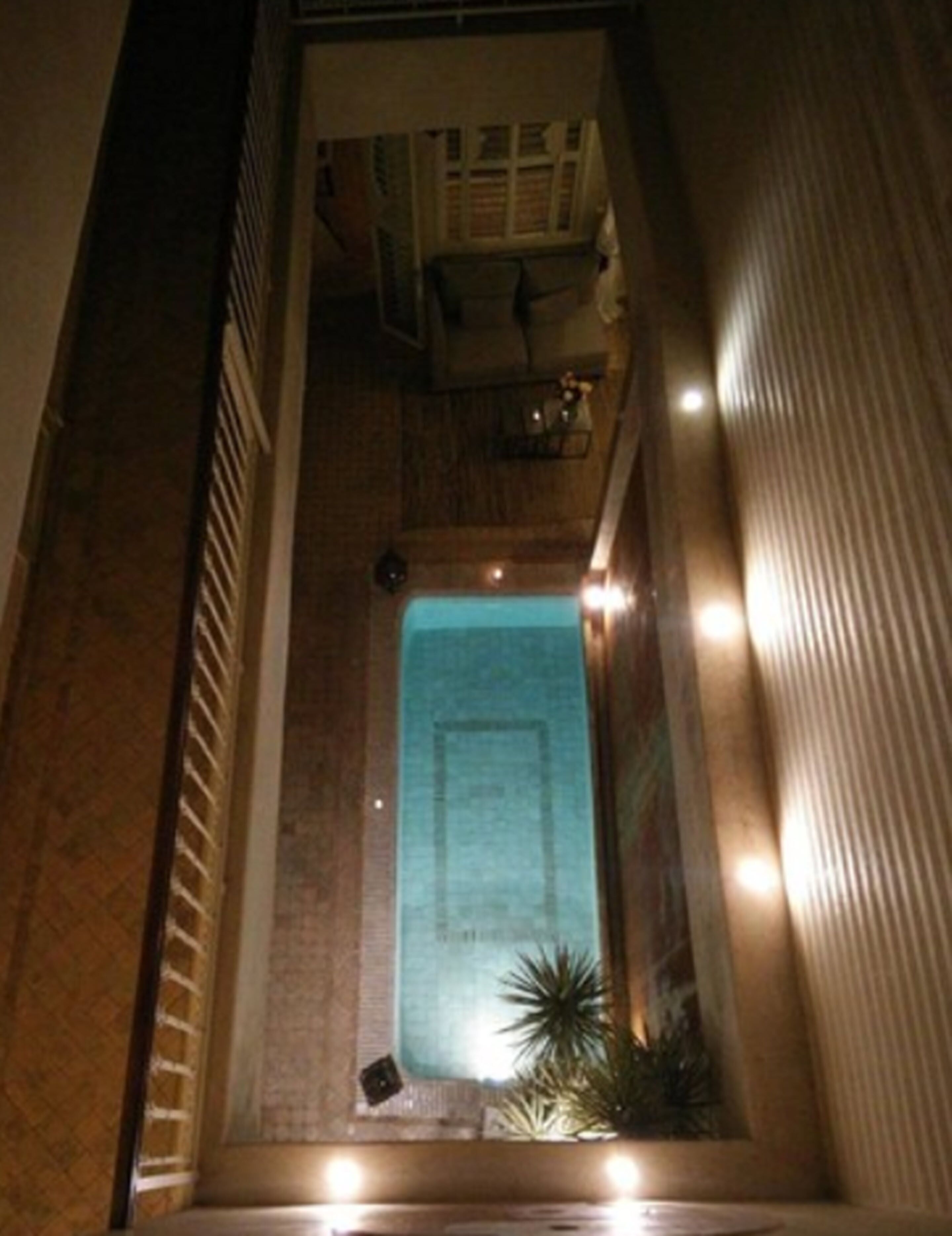 A narrow, enclosed space with a small pool at the center, surrounded by walls and a ceiling with lights.