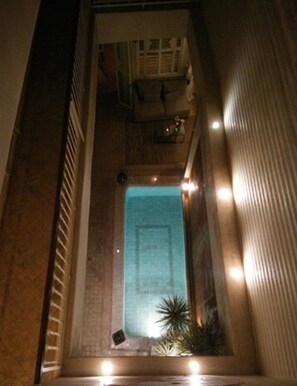 A narrow, enclosed space with a small pool at the center, surrounded by walls and a ceiling with lights. - Riad Cocoon (Marrakech)