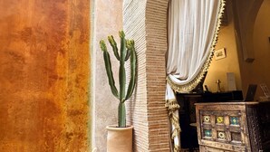 A cactus in a pot, a wooden cabinet with decorative tiles, and a curtain with tassels. - Riad Cocoon (Marrakech)