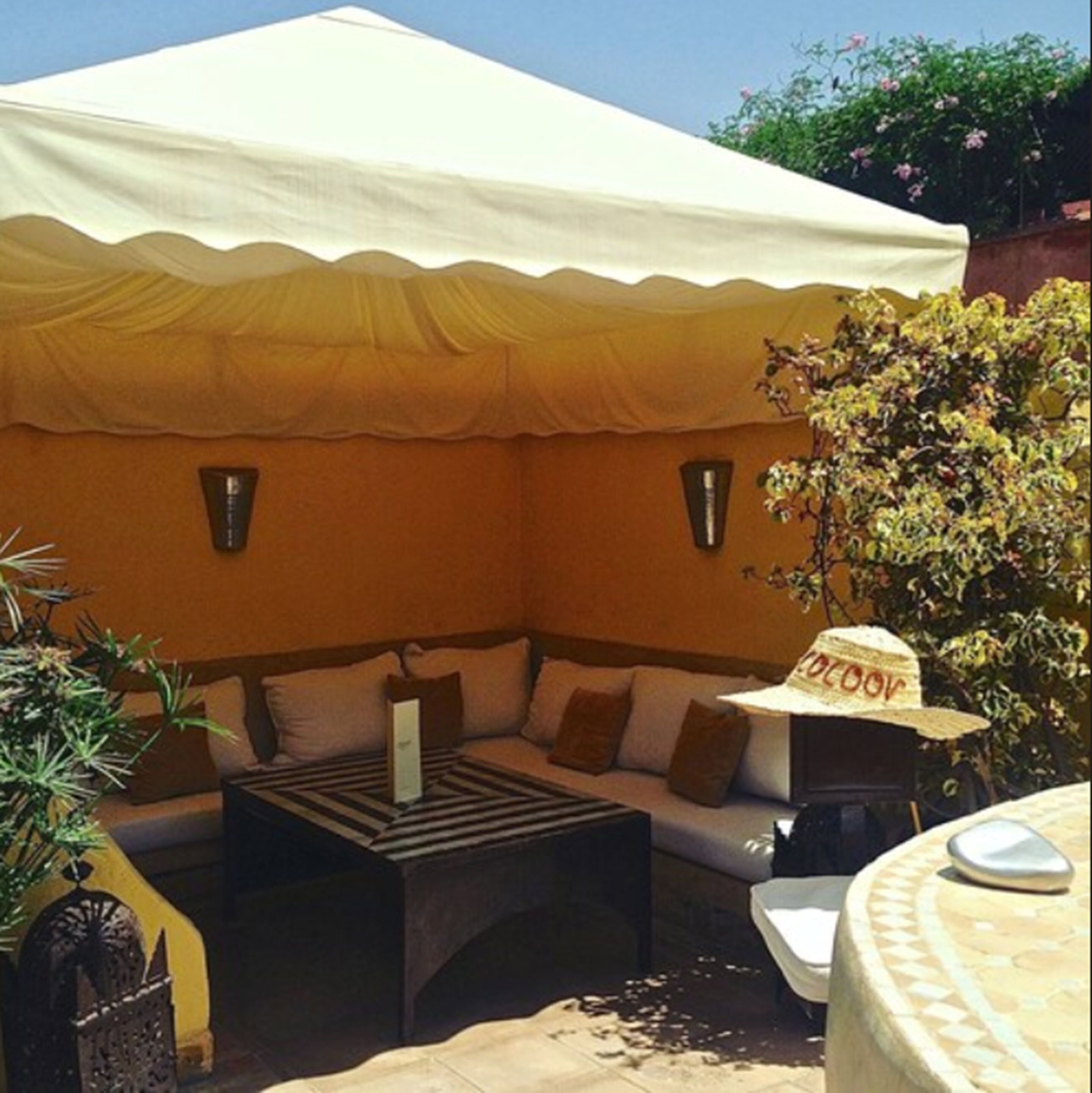 An outdoor seating area with a sofa, a table, and a hat.