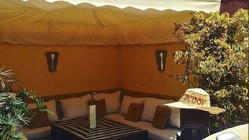 An outdoor seating area with a sofa, a table, and a hat.