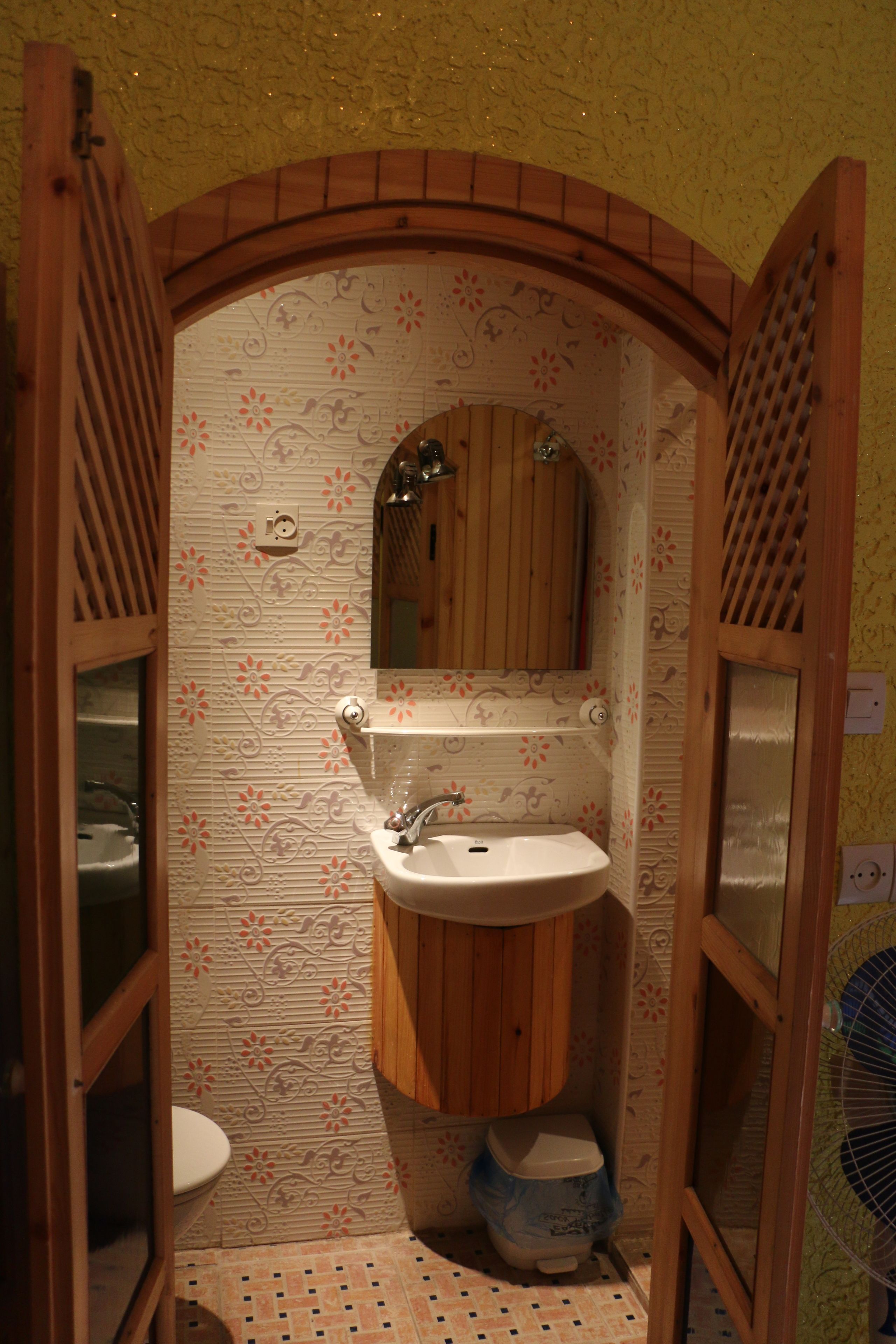 Un baño con tocador de madera, lavamanos, espejo y retrete.