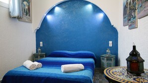 A room with a bed, two nightstands, a lantern, and a wall with a blue textured design. - Riad les Chtis d'Agadir (Agadir)